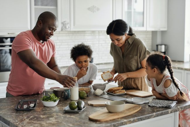 A family of four gathered around a kitchen counter for breakfast