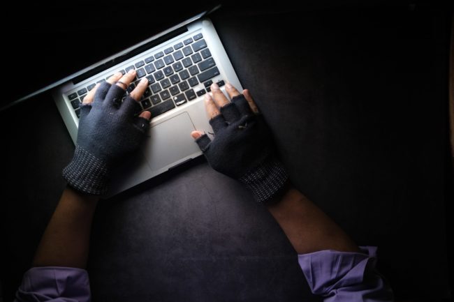 man in fingerless gloves types on computer